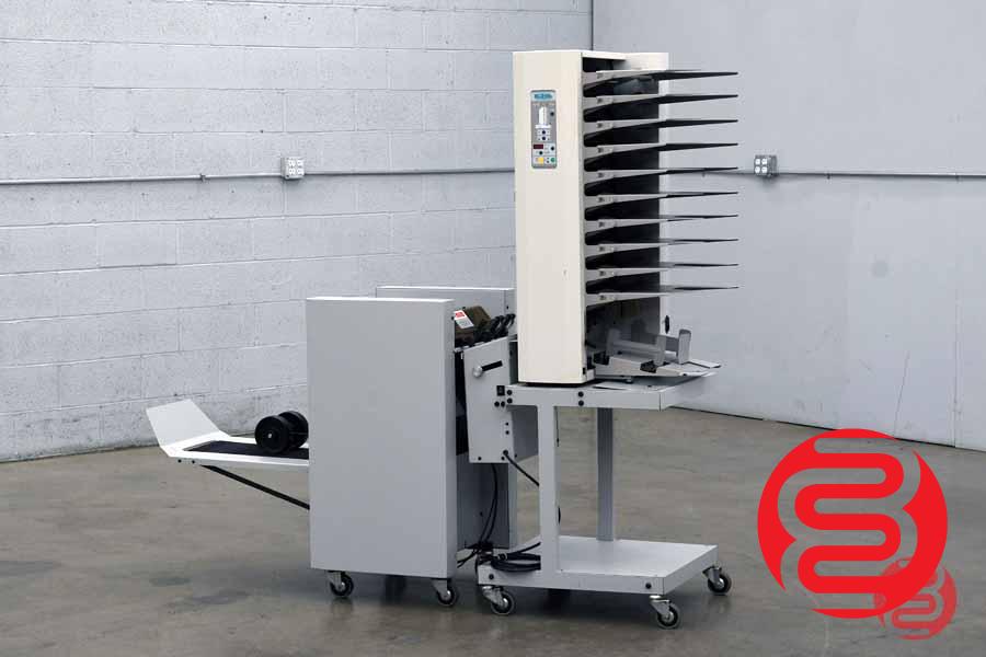 Dealer (Boggs) photo of the Baum/Plockmatic 310 system: 10-station vertical friction-fed collator tower on castors, feeding a bookletmaker/stitcher-folder with delivery conveyor. Warehouse floor setting. NOTE: red Boggs logo watermark bottom-right — reviewer to decide whether to keep or replace with