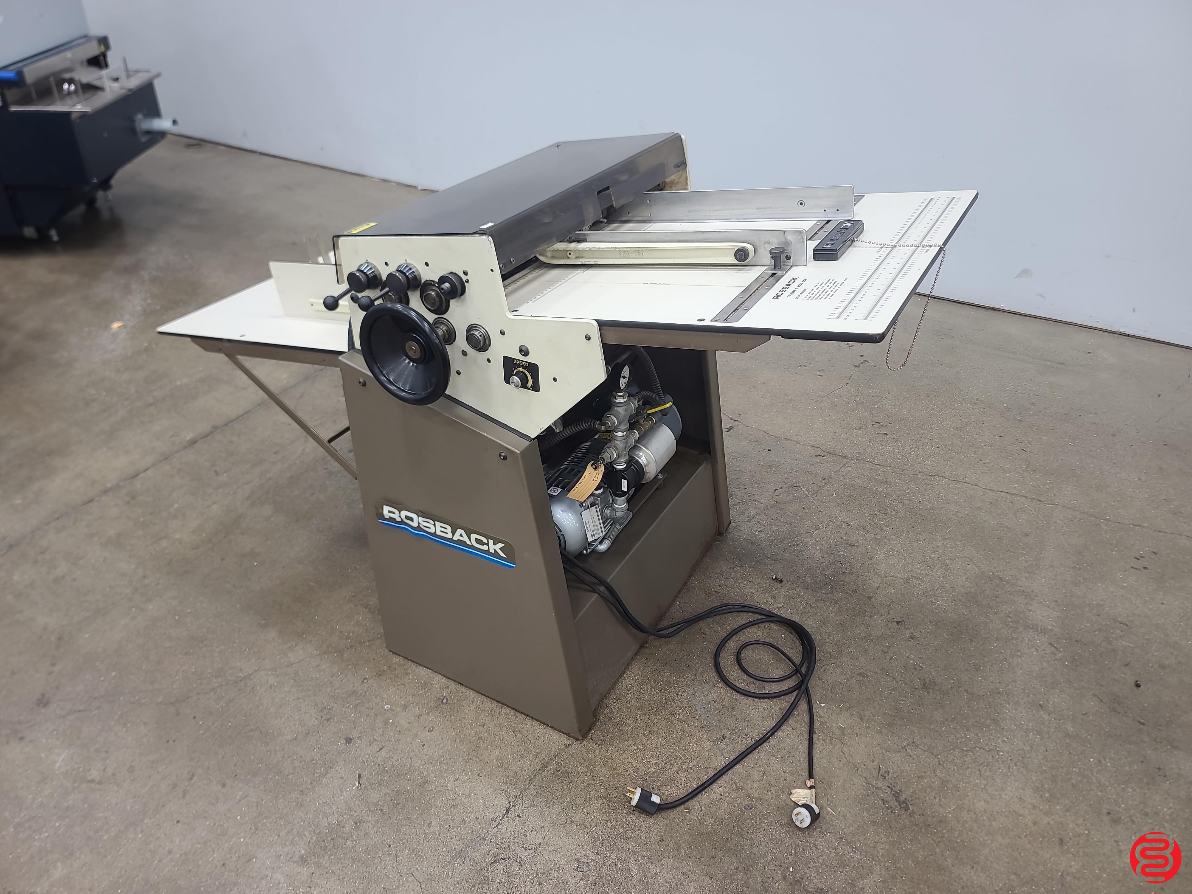Dealer (Boggs) photo of a Rosback True Line vacuum-feed perforator/scorer/slitter, ROSBACK badge on the cabinet, vacuum pump exposed in the base, head rail with multiple adjustable heads and control knobs. High-res. NOTE: small Boggs red-logo watermark bottom-right — reviewer to decide whether to ke