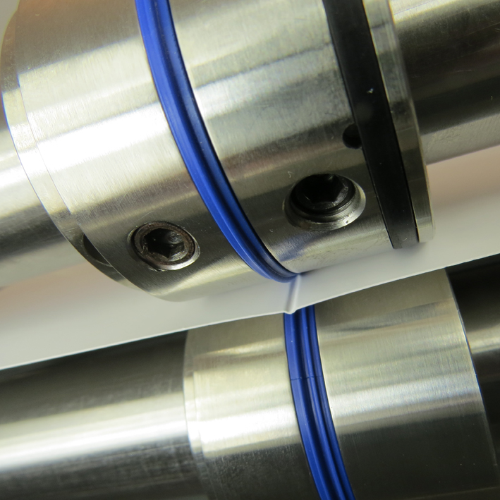 Close-up of Fast-Fit tools with blue ribs creasing paper in folding machine