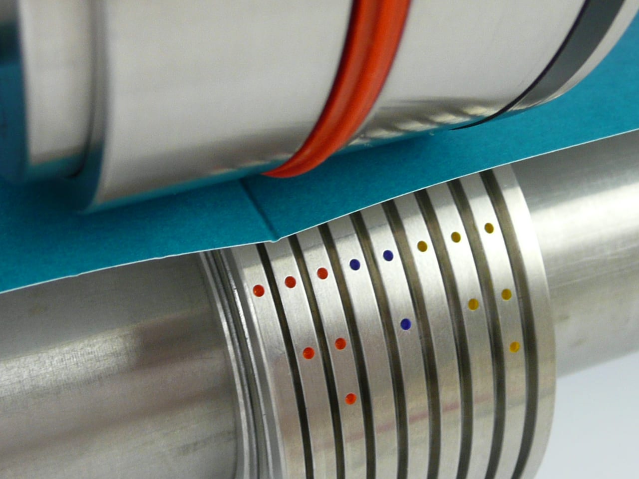 Creasing rib pressing teal stock into its colour-coded channel on the shafts