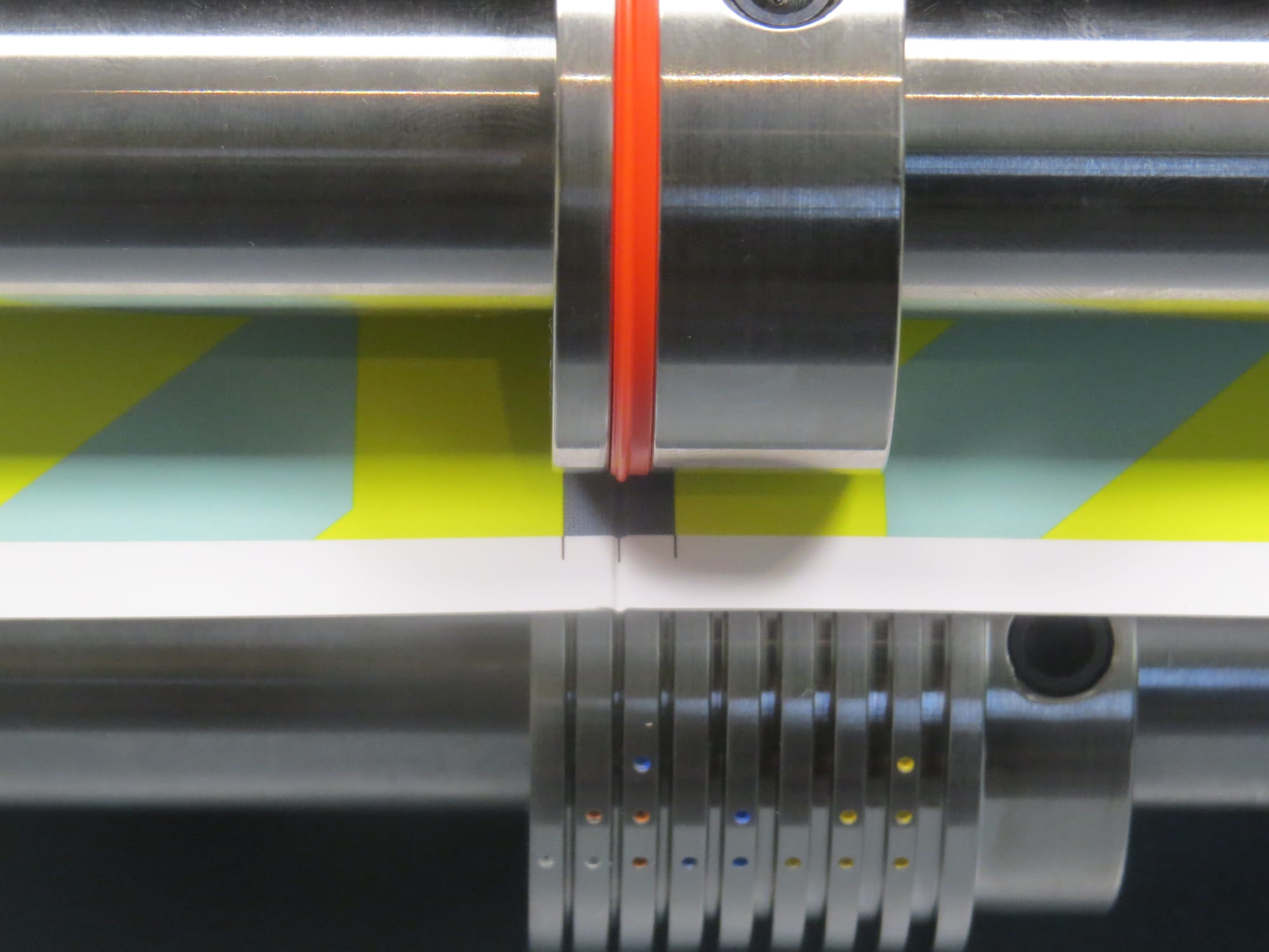 Section-Scorer band pressing a deep score into printed stock as it runs between the folder shafts